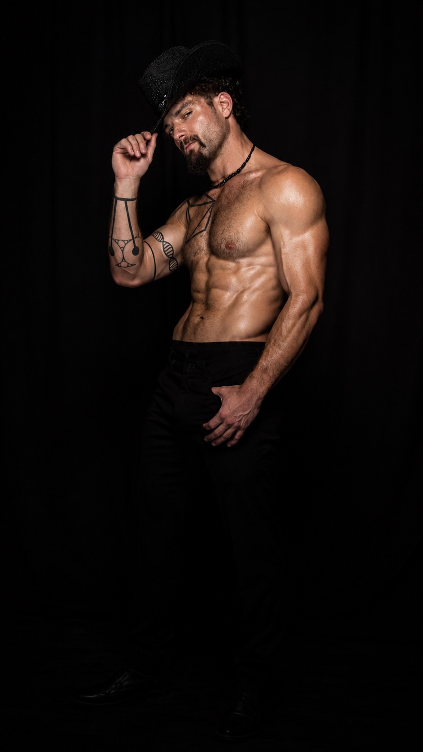 Hardbodies Live dancer tipping his black hat in a studio portrait