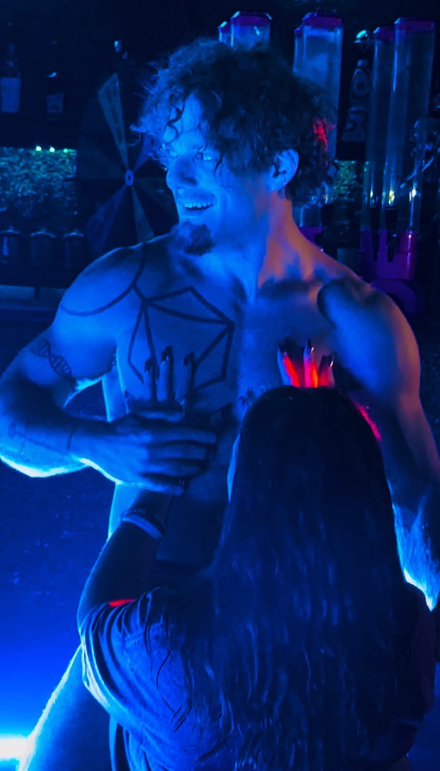 Hardbodies Live performer smiling and interacting with a guest under blue stage lights